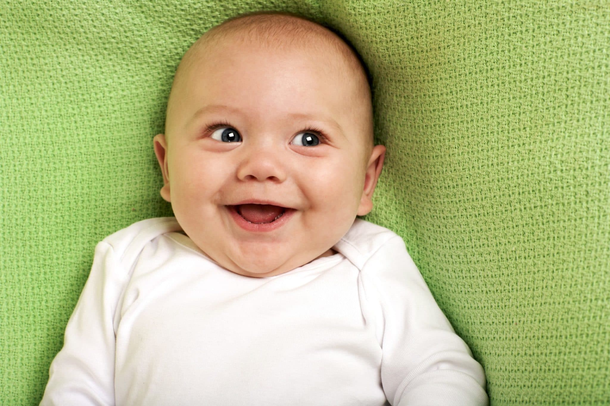 bébé souriant sur une couverture verte