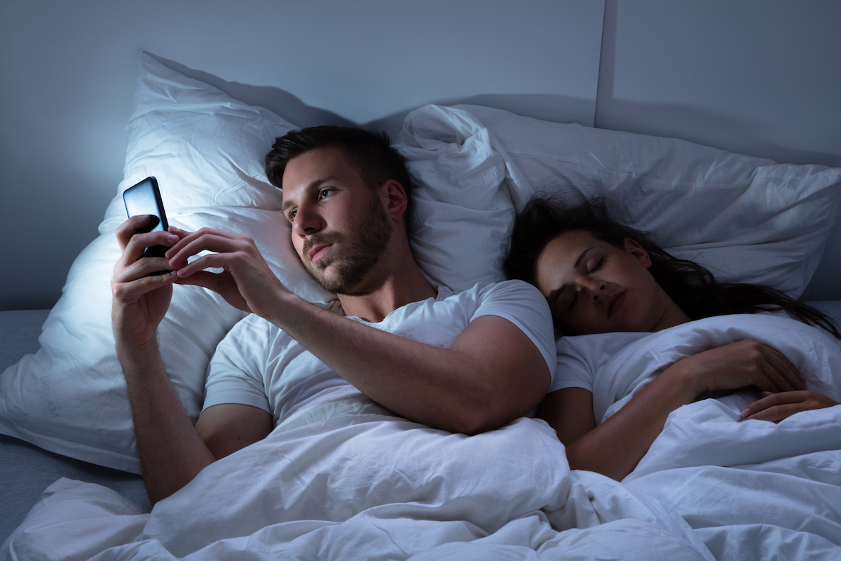 homme qui envoi des sms pendant que sa femme dort