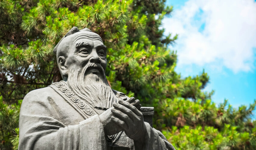 statue de confucius devant un arbre