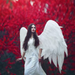un ange ailé sous un arbre rouge