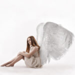 un ange ailé assis sur le sol 