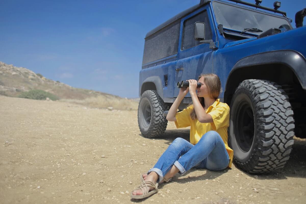 femme assise contre sa voiture dans le désert