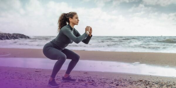 curly-sports-woman-in-sportswear-faisant-exercices-squats-plage