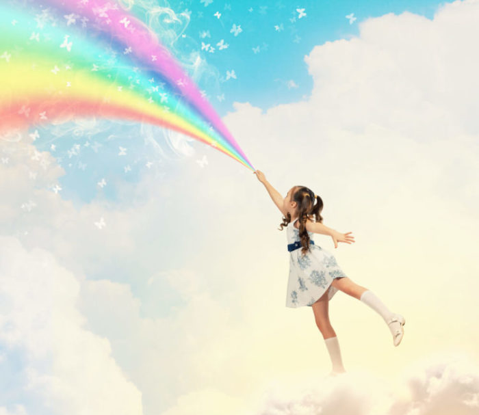 enfant sur un nuage devant un arc-en-ciel