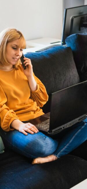 femme-parlant-au-telephone-aide-son-ordinateur-portable-canape-maison