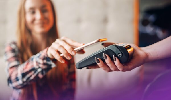 Young woman pay by mobile phone in cafe. Modern payment technologies