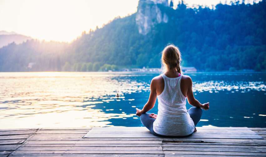 jeune femme qui fait de la meditation devant un lac