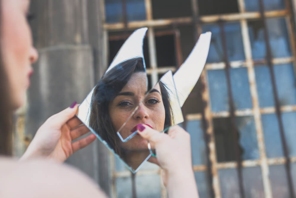 femme qui se regarde dans un miroir brisé