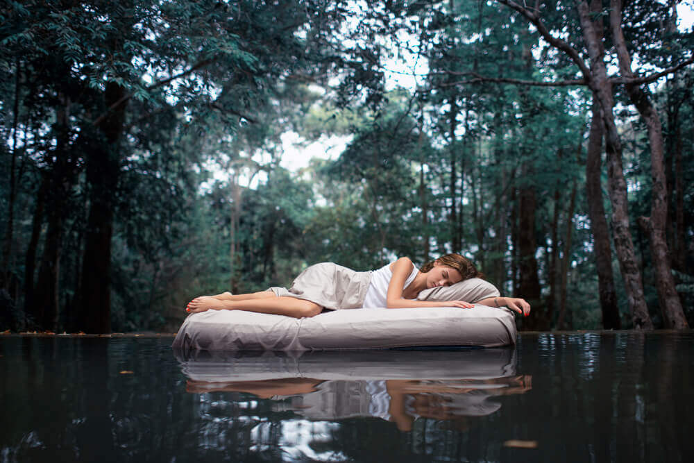 femme dormant sur un matelas au milieu d'un lac 