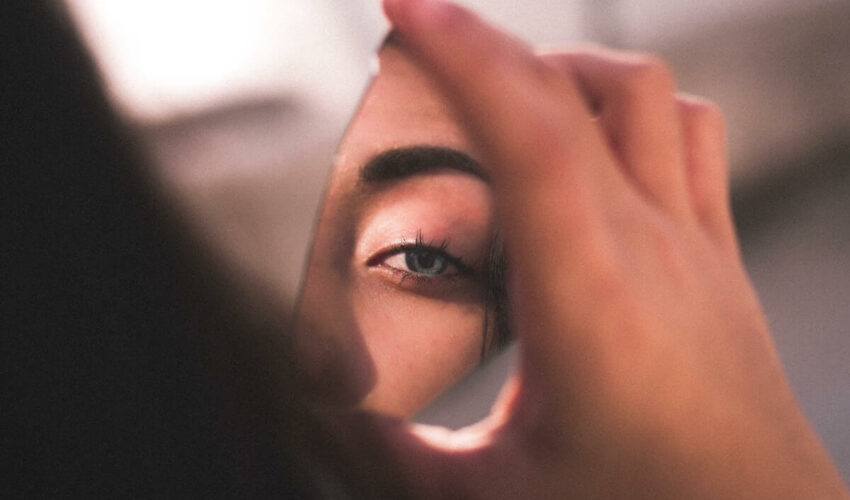 femme qui se regarde dans un miroir brisé