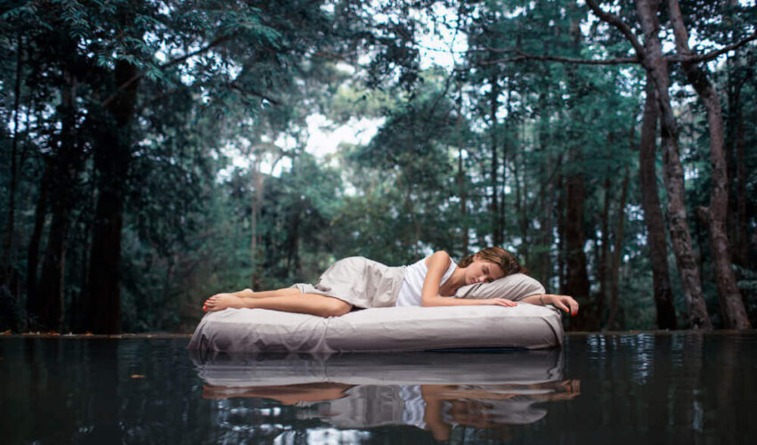 femme dormant sur un matelas au milieu d'un lac