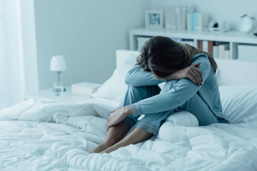 femme déprimée assise sur un lit